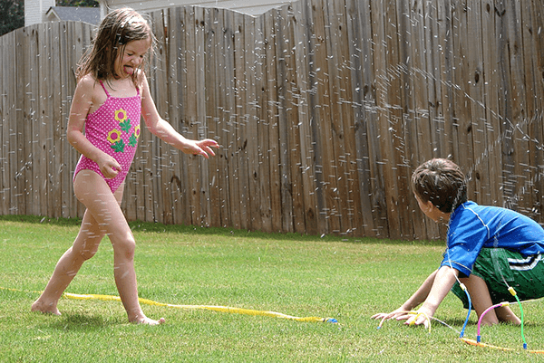 Children playing in sprinklers outside in the summer