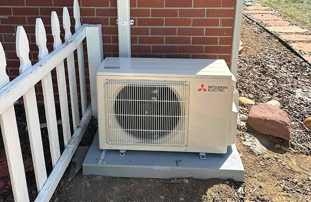 an outdoor mini split condenser unit against a brick wall