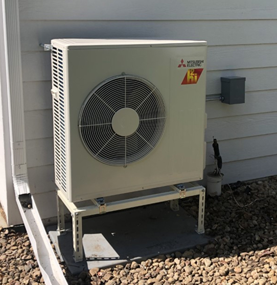 an outdoor condenser mini split unit in front of a blue wall