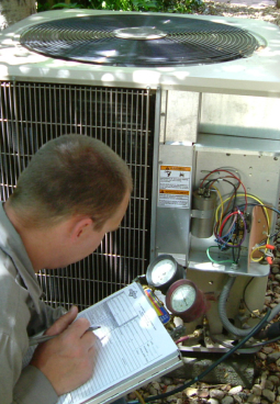 an hvac technician writing something while inspecting an hvac system