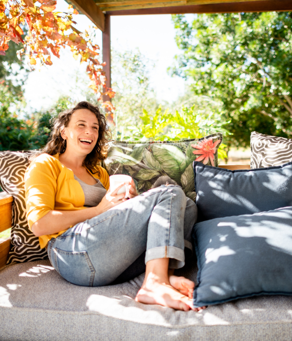 women sitting under a shaded sofa with a mug